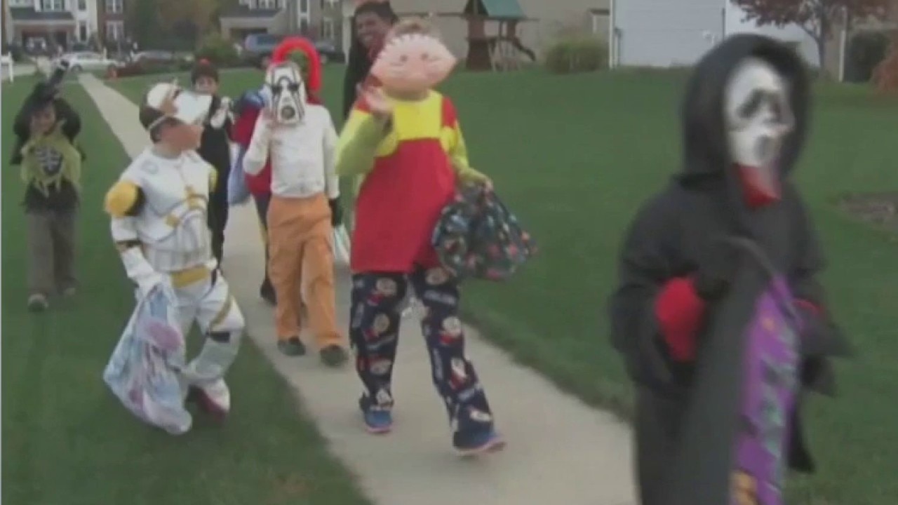 Children in costumes celebrating Halloween in a festive neighborhood